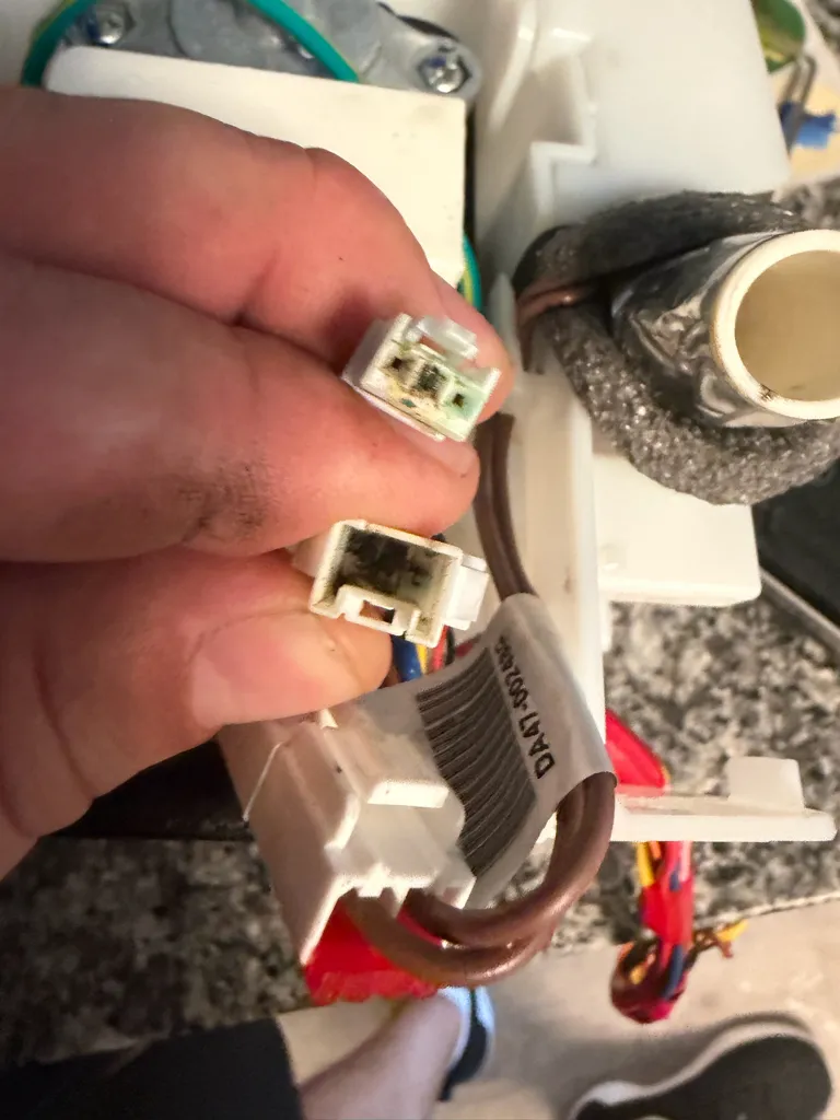 Two white connectors held in a hand, with dark corrosion on the contacts