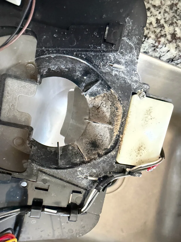 Removed Samsung dispenser door assembly with white mineral deposits and debris, over a sink